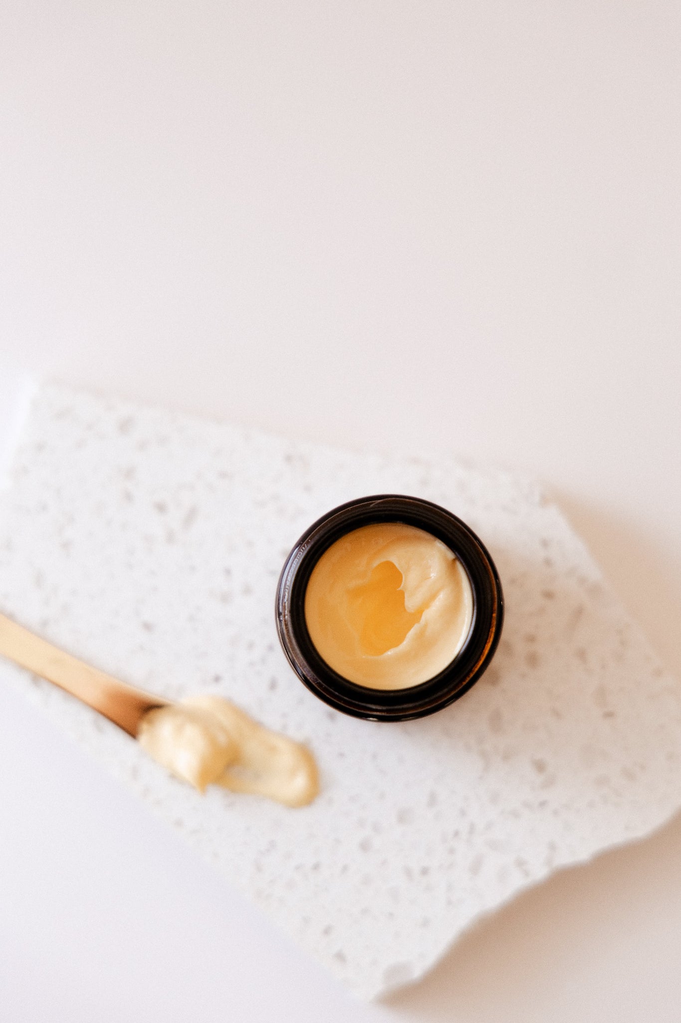 Eye Cream with a golden applicator on a marble surface