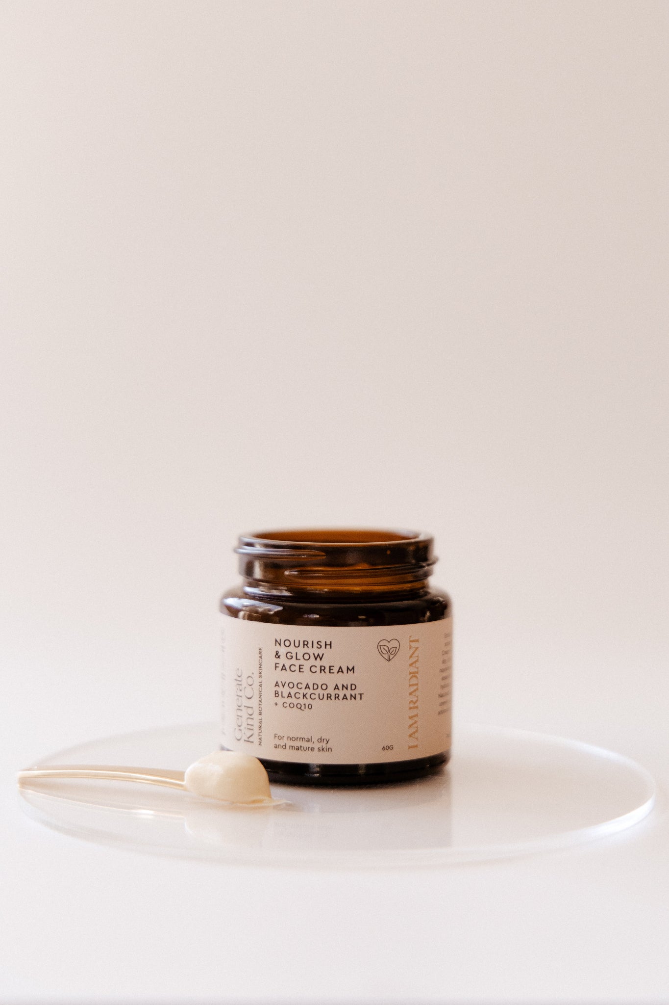 Jar of Nourish & Glow cream with a gold spoon of cream on a white background