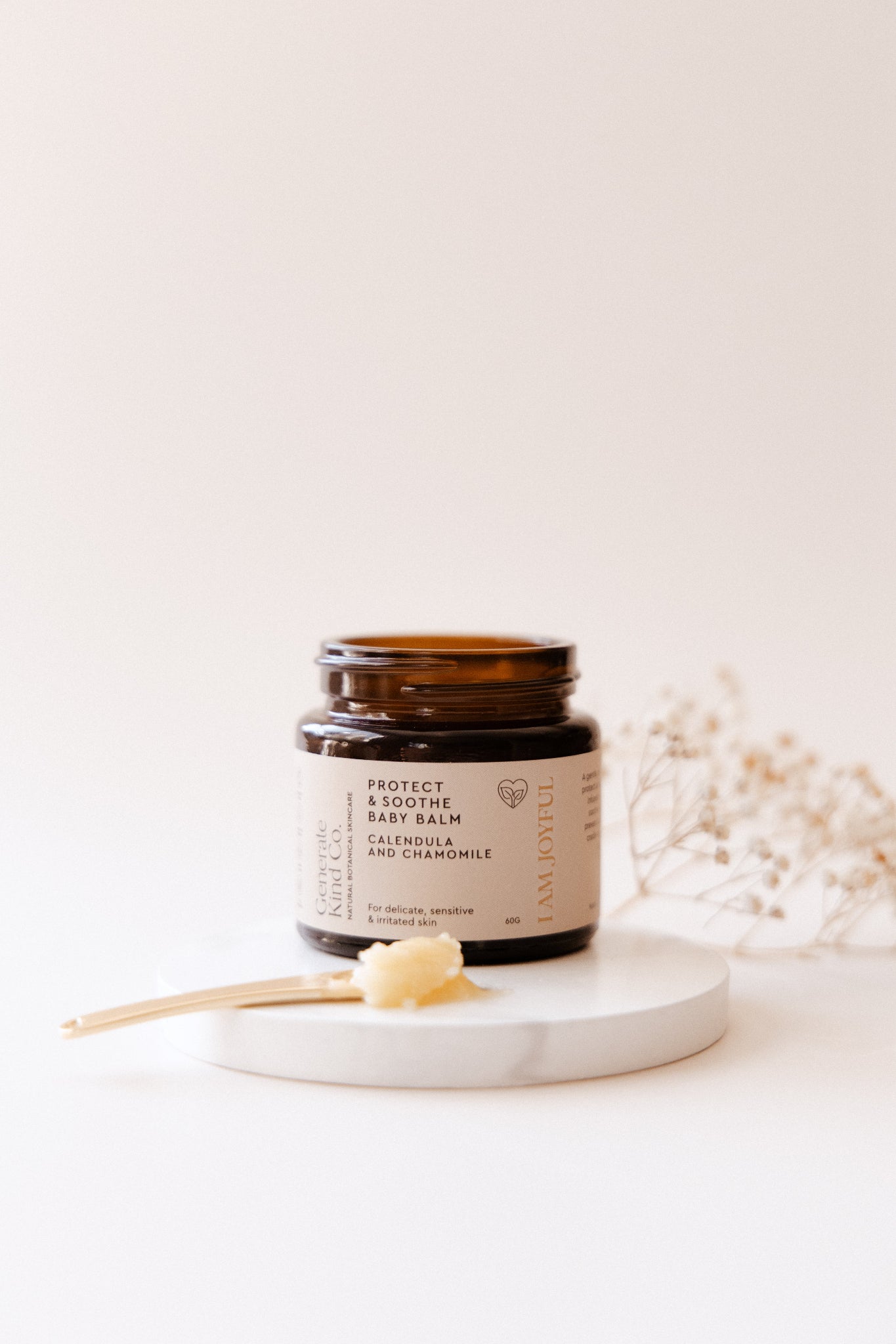 Baby Balm on ceramic tray with golden applicator spoon and balm on to show texture