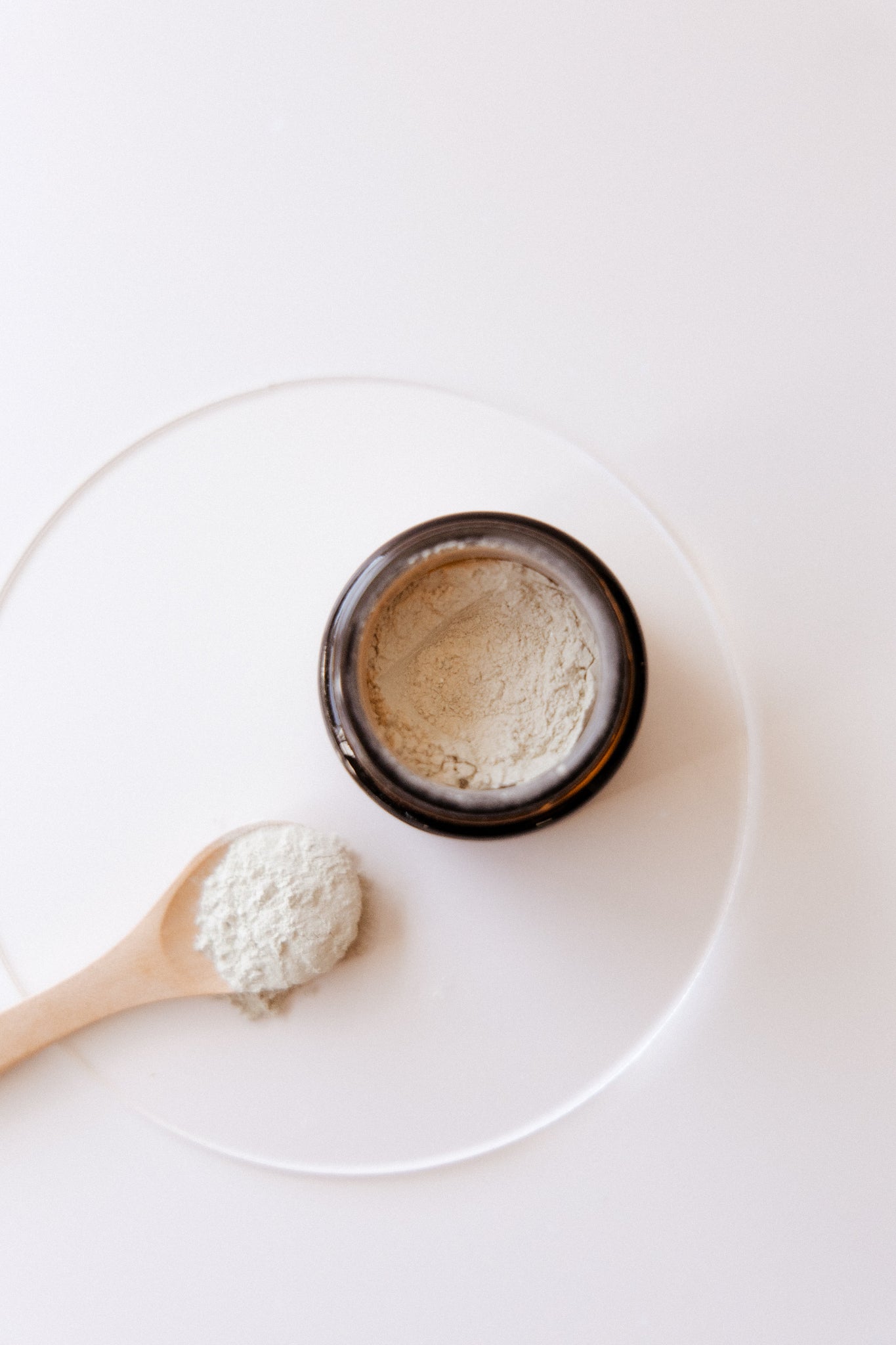 Green Clay Face Mask Texture shot with a wooden spoon on a white surface