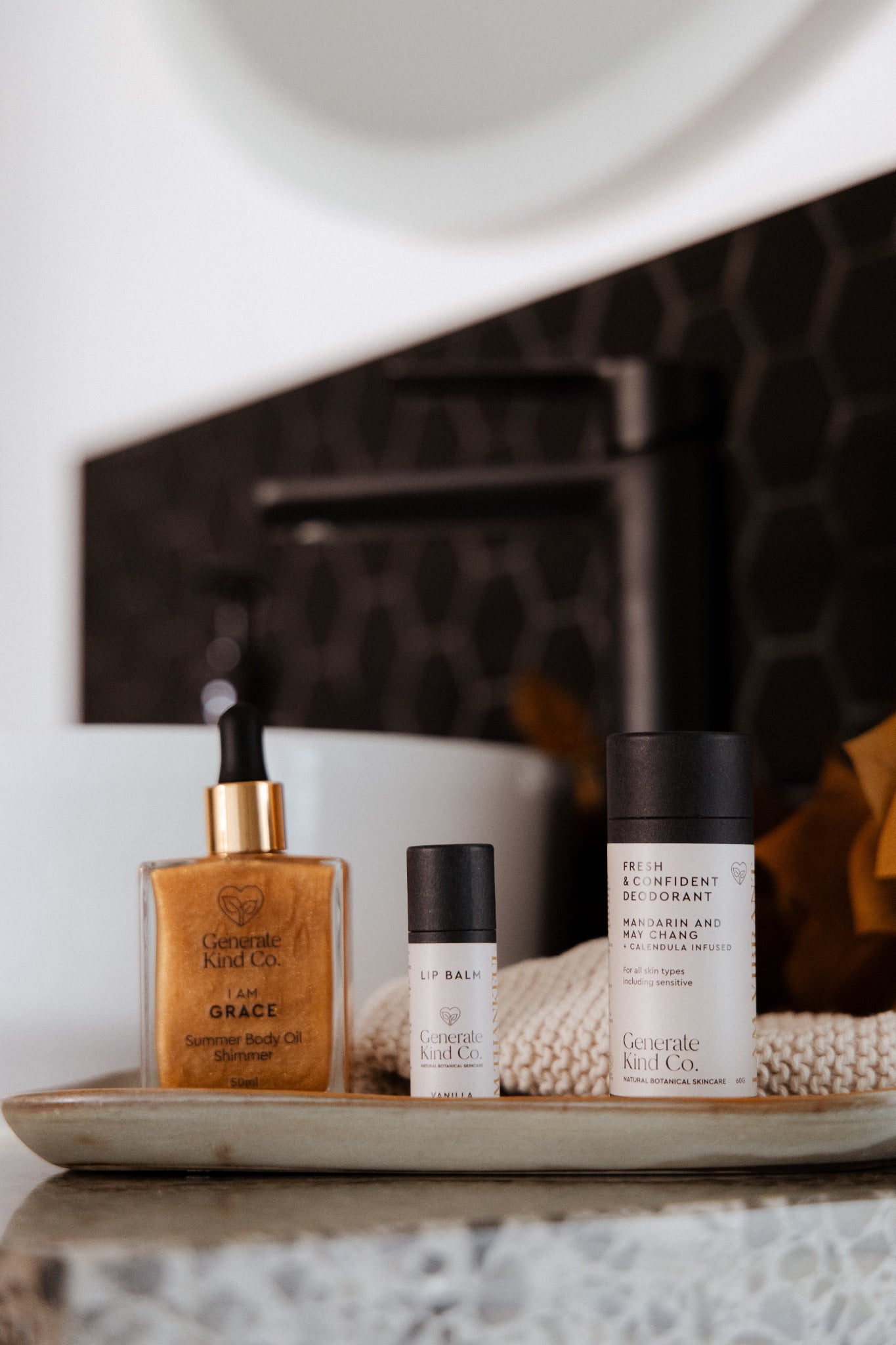 Generate Kind CO. Body care essentails, lip balm, natural deodorant and Shimmer body oil on a tray in bathroom