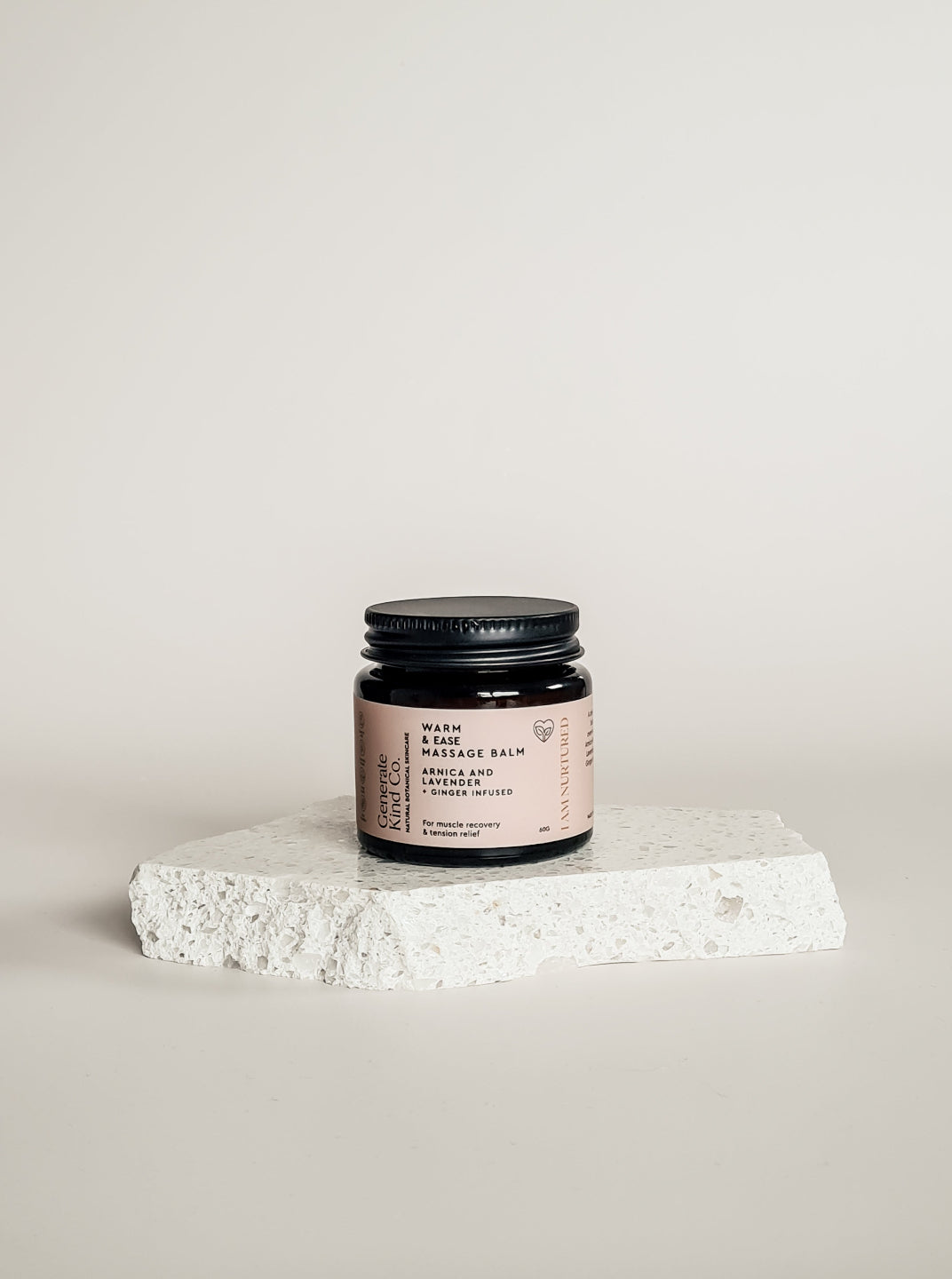 Jar of massage balm on a white stone surface with a light gray background