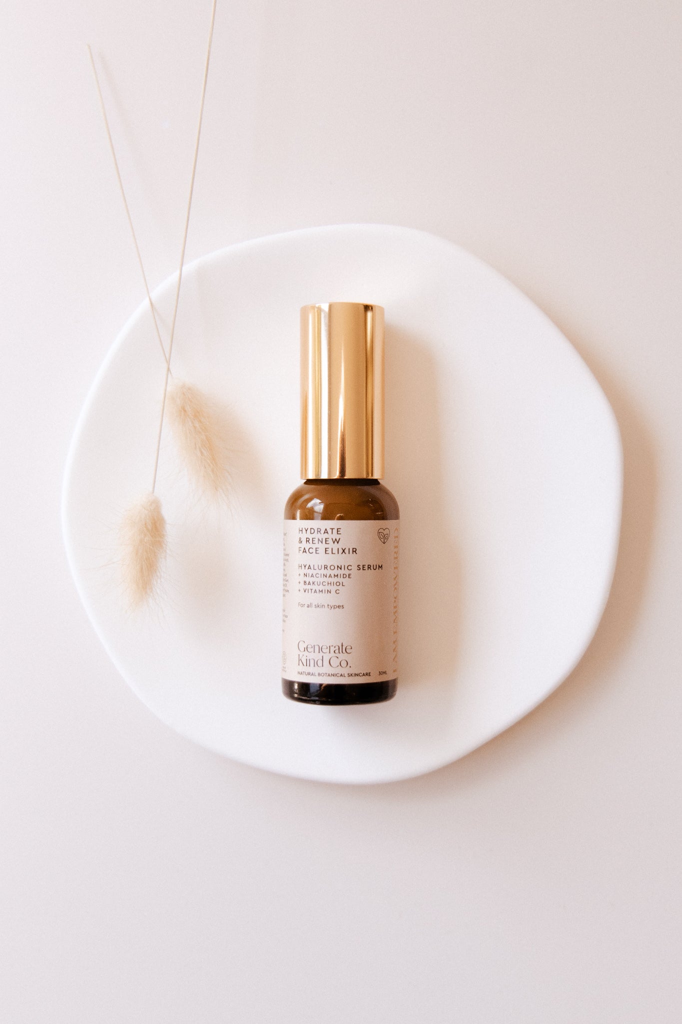 Gerenate Kind Co. Face Elixir serum bottle on a white plate with a neutral background