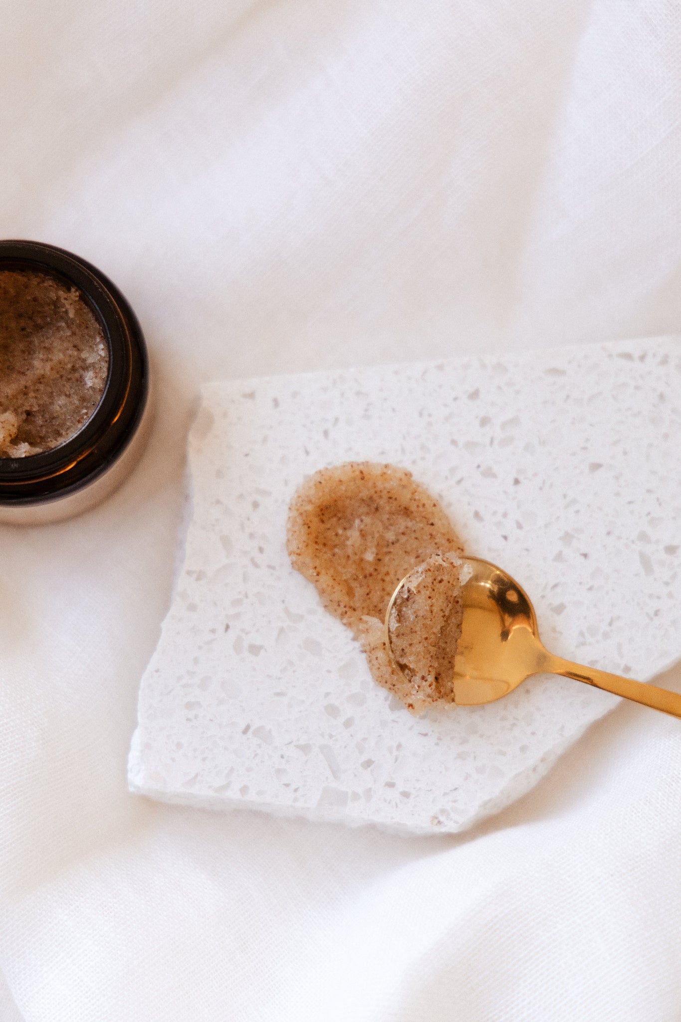 Generate Kind Co. Sugar Body scrub on a marble surface showing texture  with a gold spoon