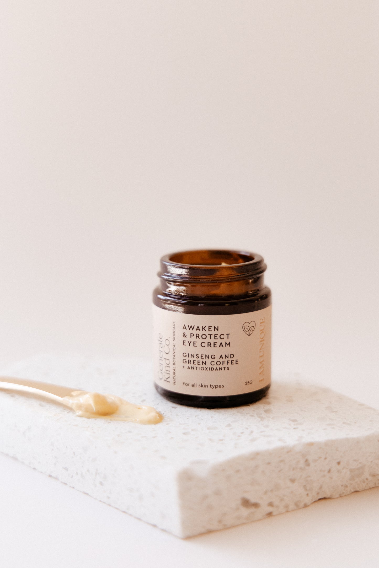 Eye cream jar with a gold applicator on marble 
