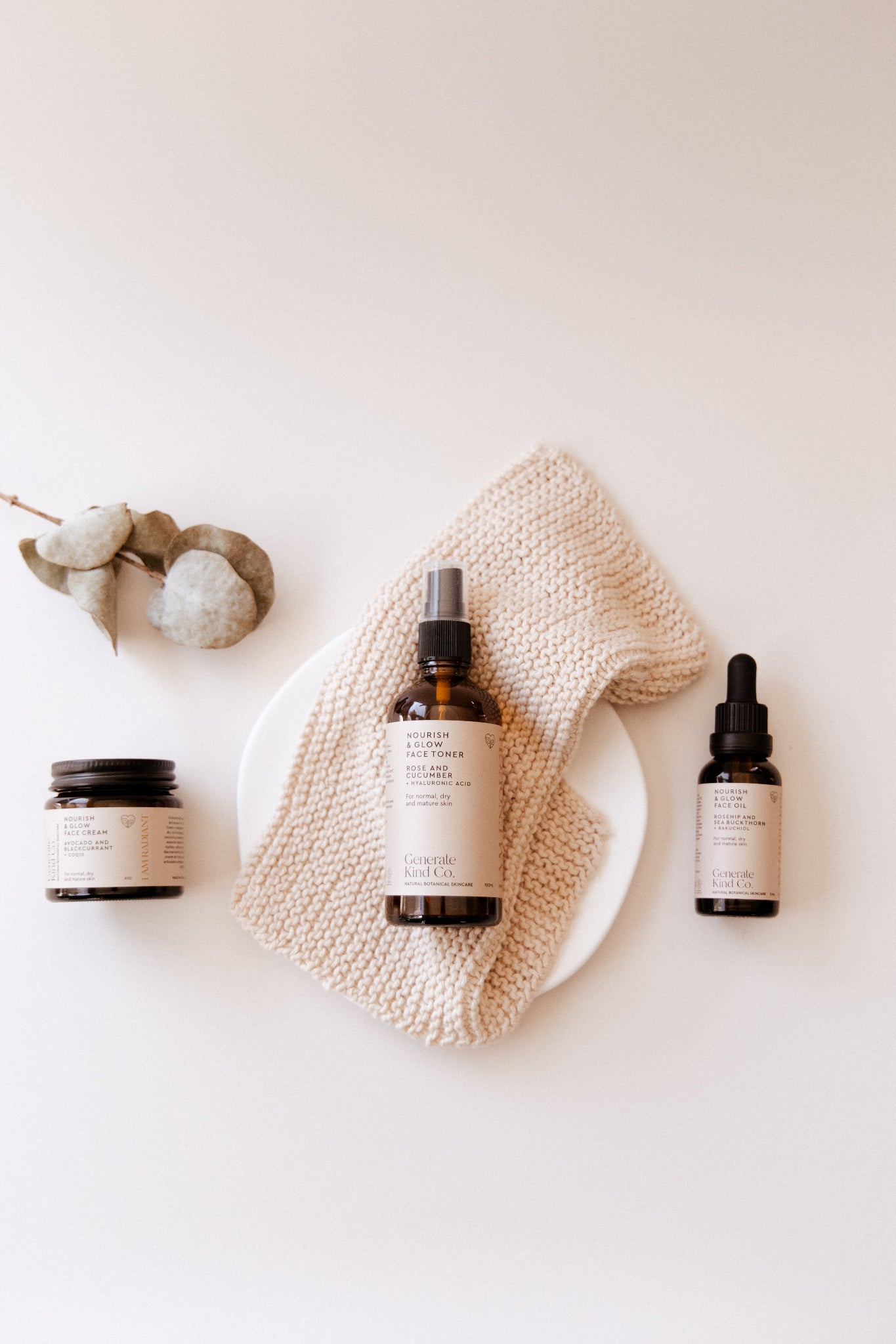 Nourish & Glow Skincare products including bottles and a jar on a textured surface with a neutral background