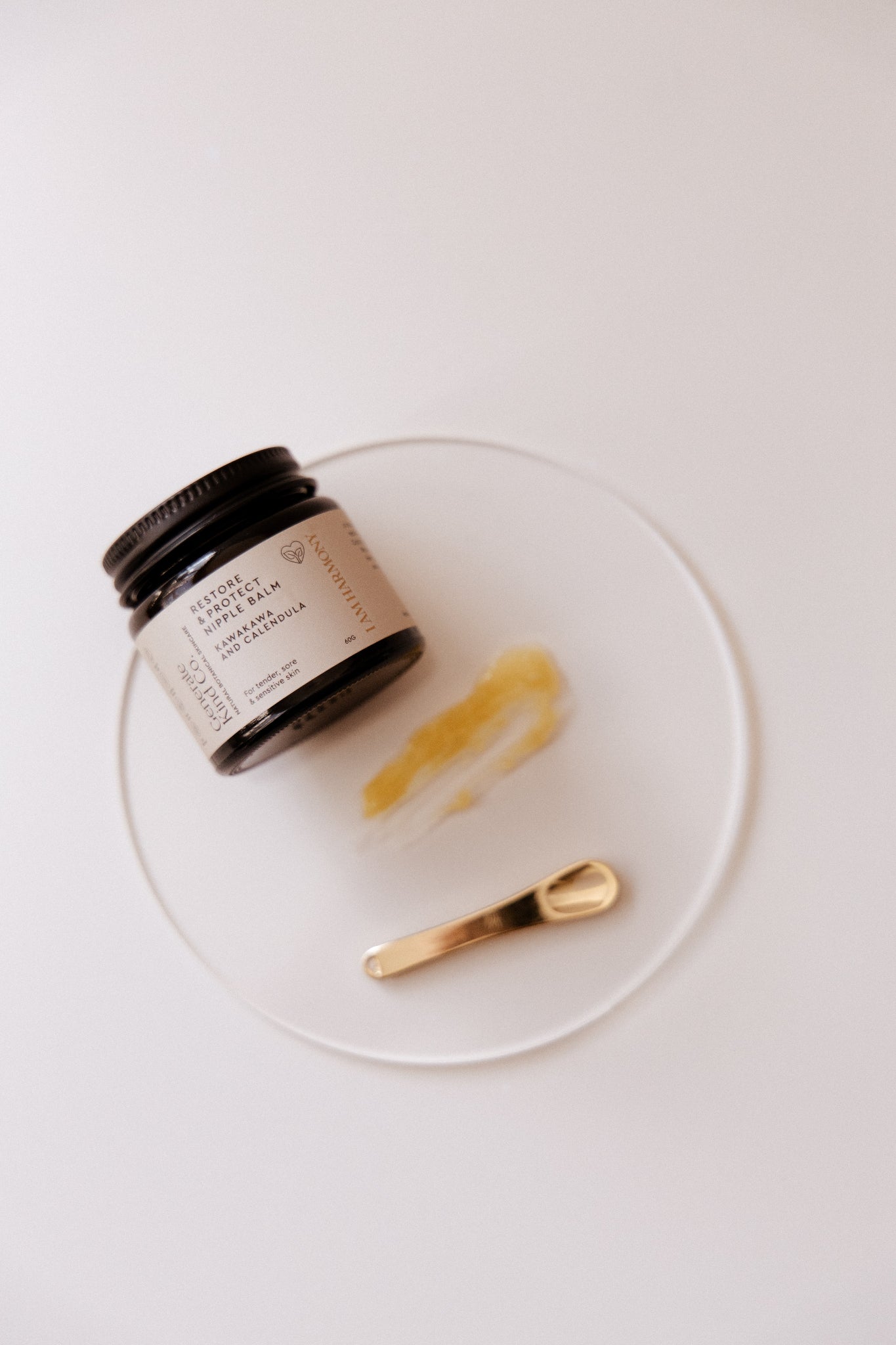 Restore & Protect Nipple Balm with a spoon on a white plate against a white background