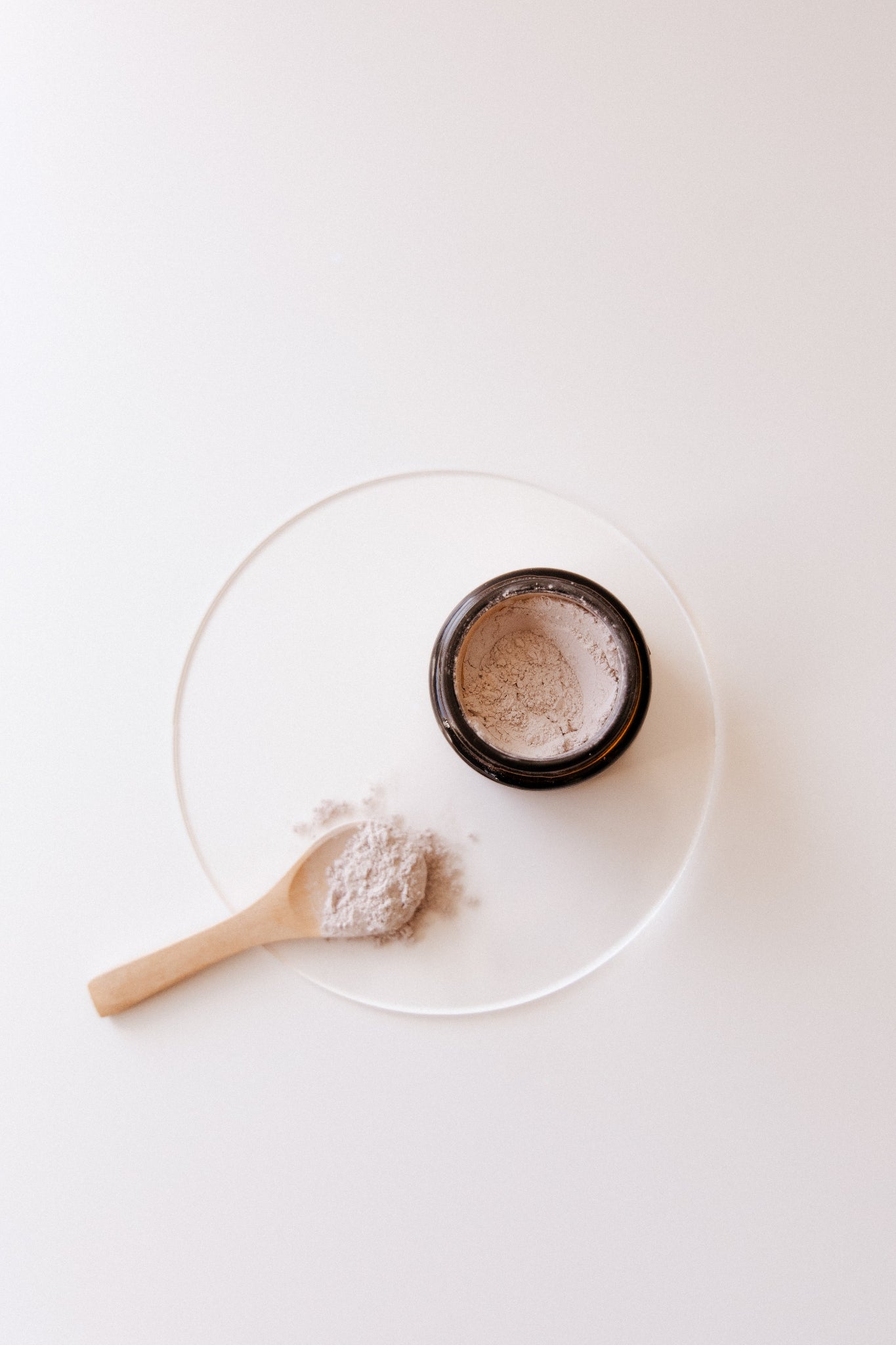 Purple Clay & Rose Face Mask with a wooden spoon on a white plate against a white background