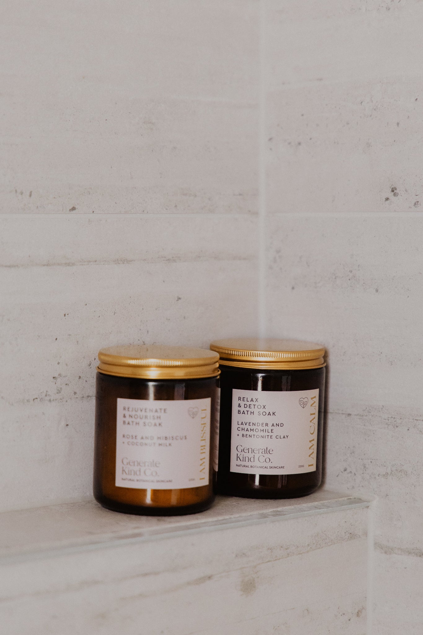 Generate Kind Co. Bath Soak Jar's sitting on a tiled bath and shower wall.