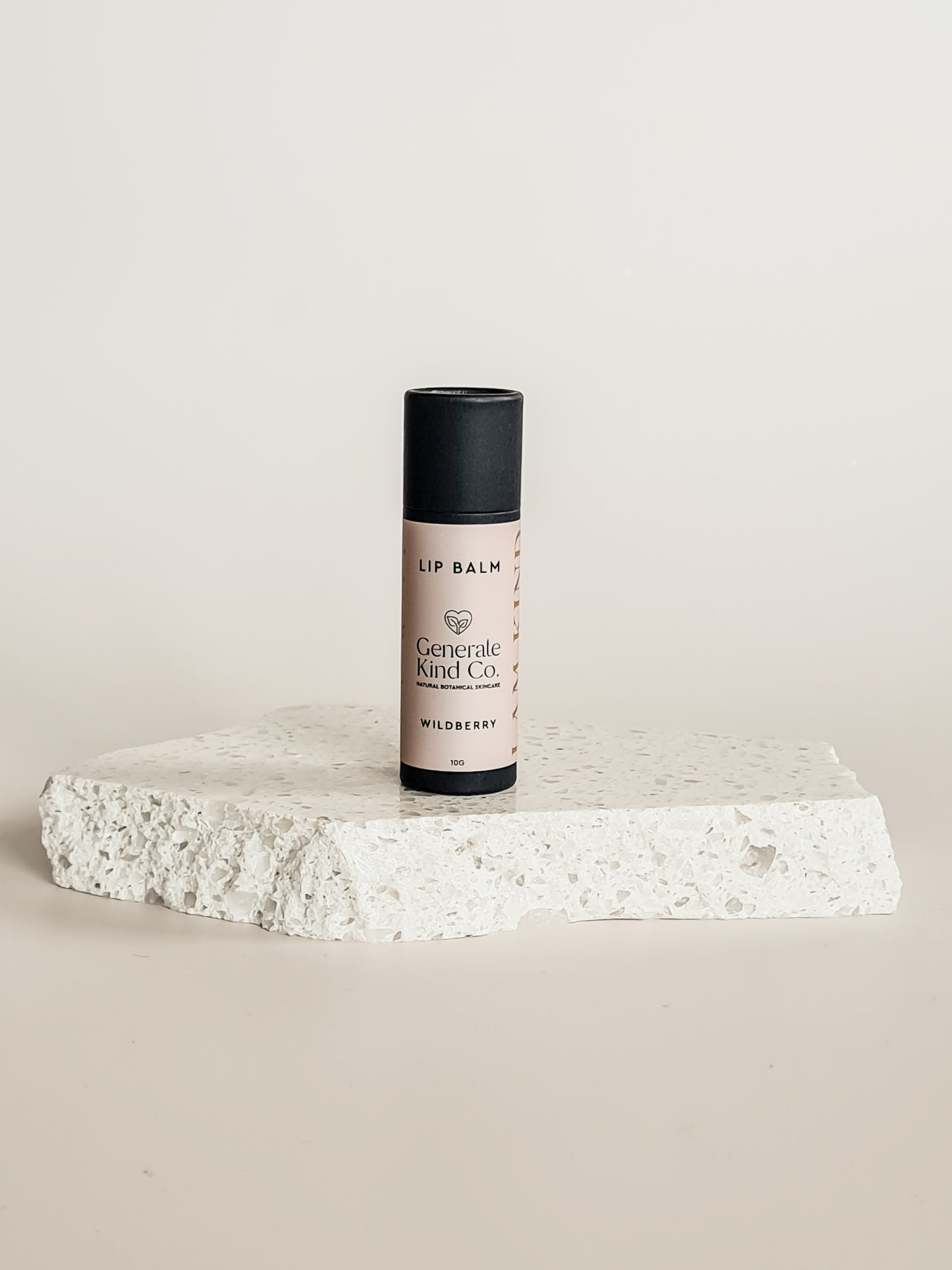 Lip balm on a textured white surface with a light gray background