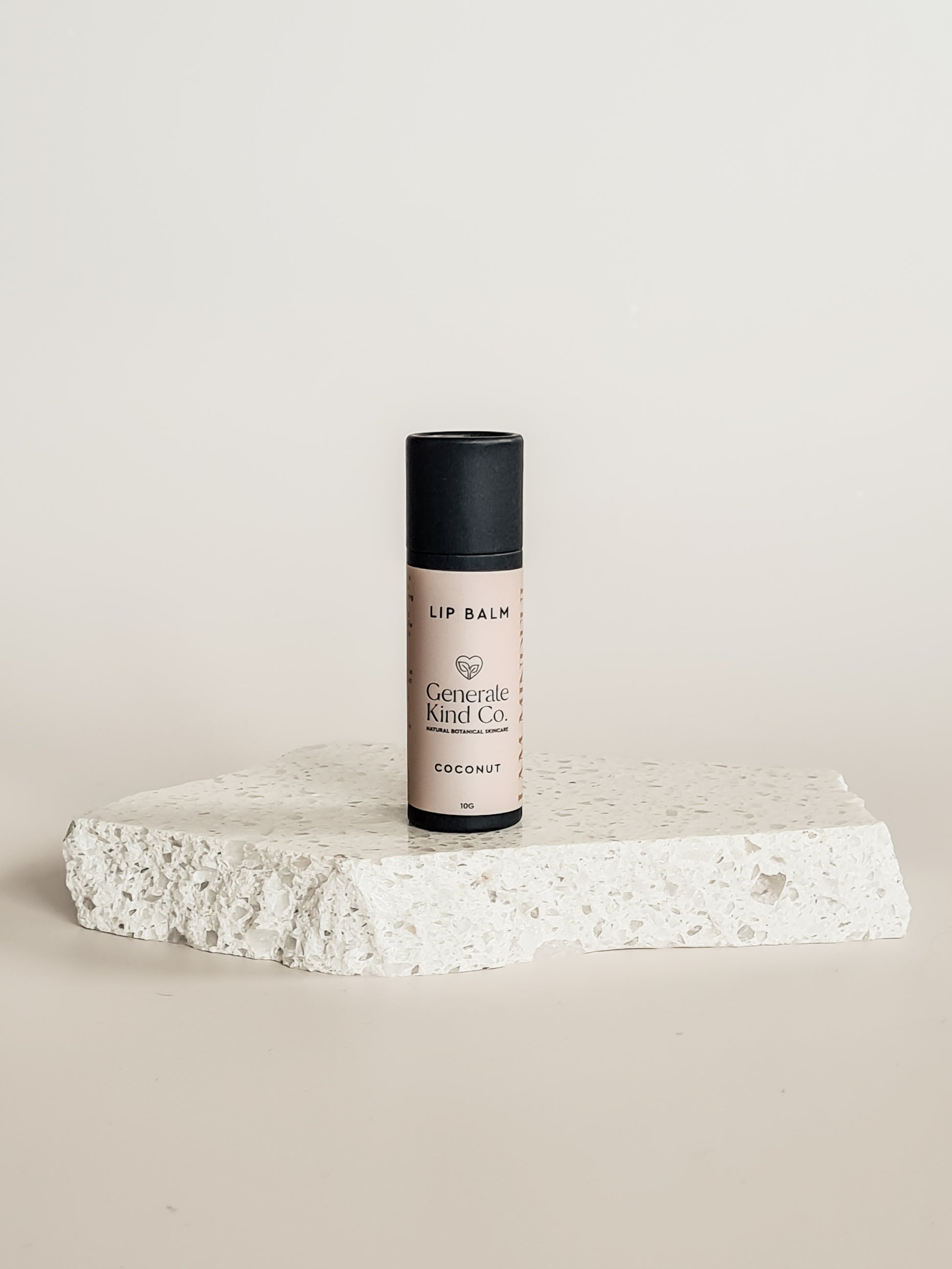 Lip balm bottle on a textured stone surface with a neutral background